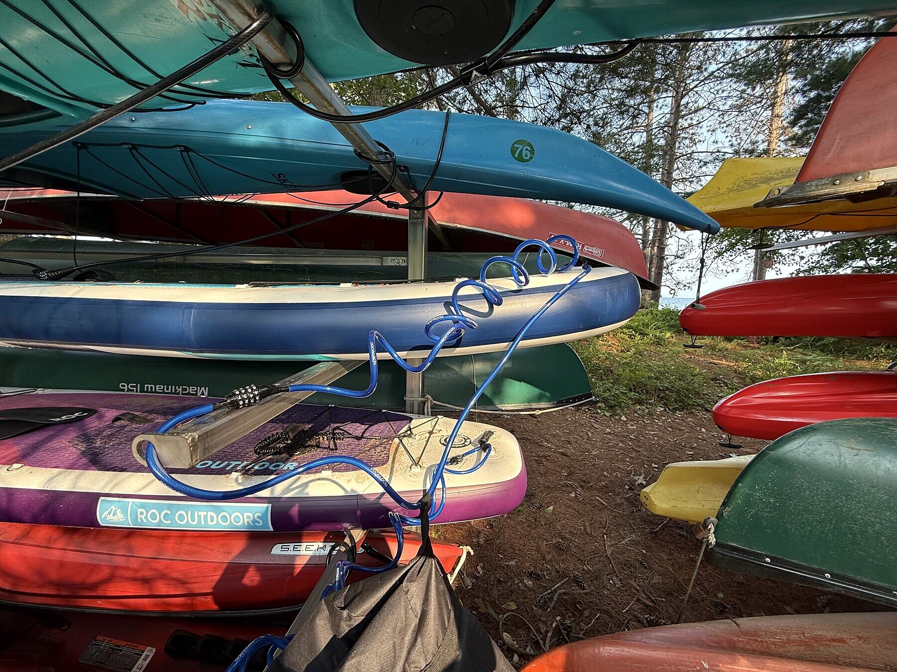 A blue cable lock coiled over paddleboards on the rack