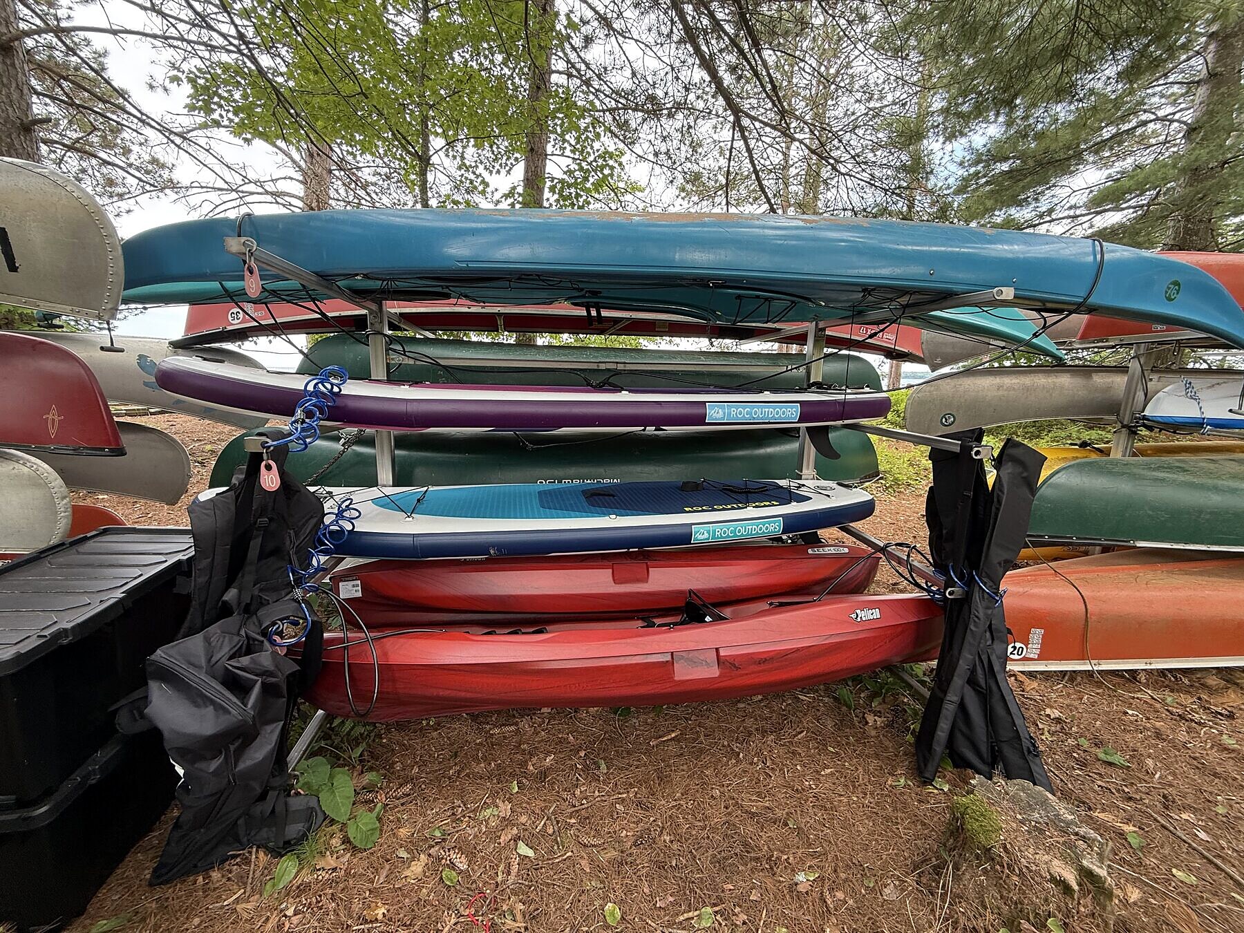 A full Madeline Adventures rack at Big Bay Town Park with kayaks and paddleboards